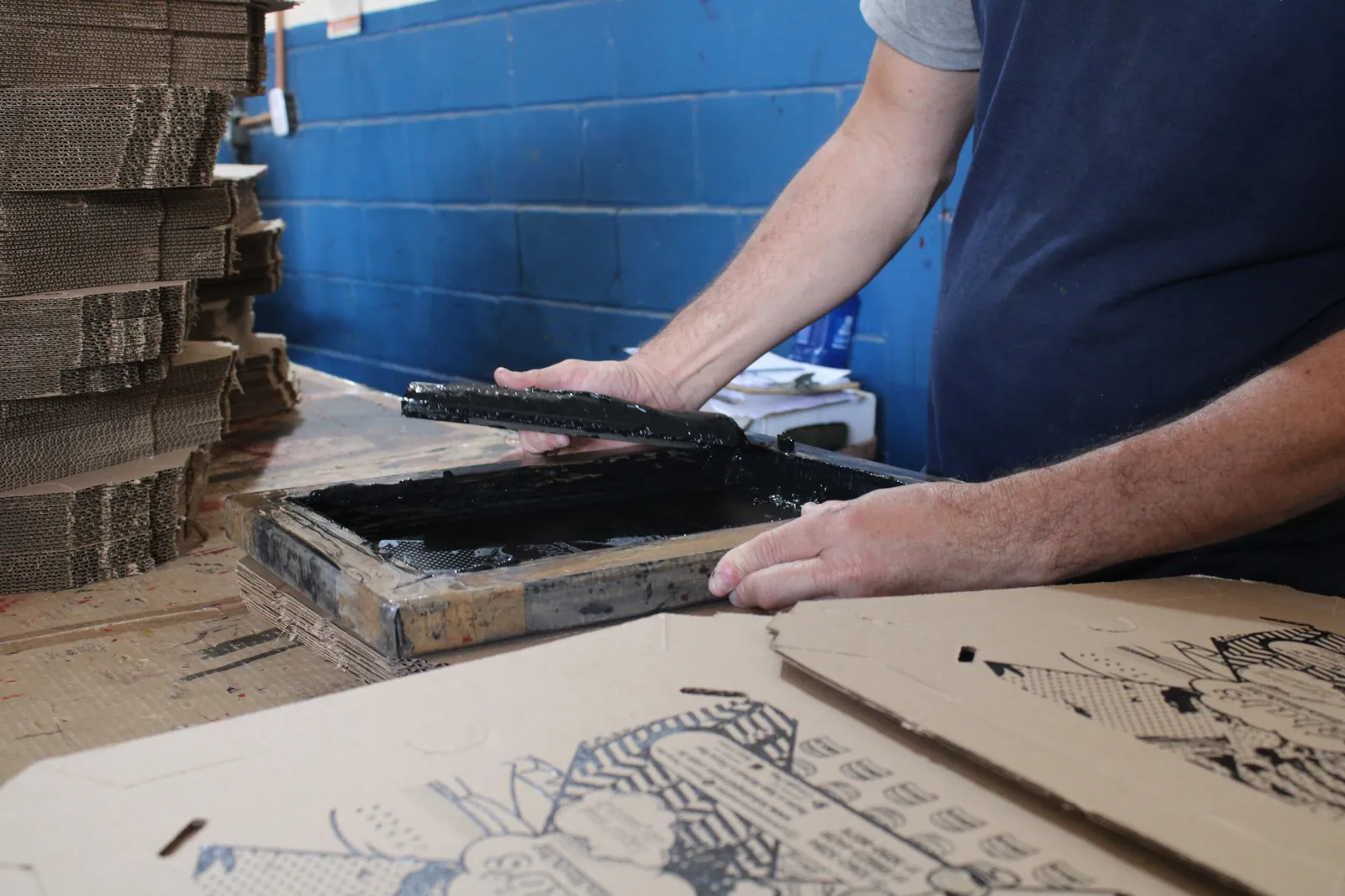 Operador aplicando tinta de serigrafia sobre uma chapa de papelão ondulado